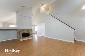 Humble house for rent - A spacious living room with a stone fireplace and wooden floors.