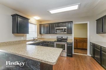 Humble house for rent - A kitchen with black cabinets and a granite countertop.