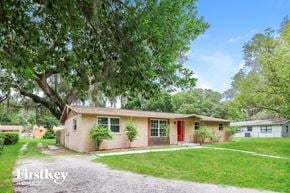 Zephyrhills house for rent - a small tan house with a red door and a tree