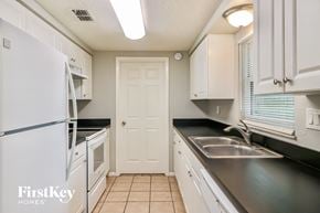 Zephyrhills house for rent - a kitchen with white cabinets and black counters and a white refrigerator and sink