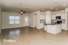 Bulverde house for rent - an open kitchen and living room with white cabinets and a wood floor