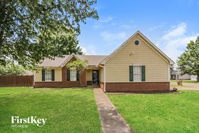 Memphis house for rent - front view of a yellow house with green grass and trees