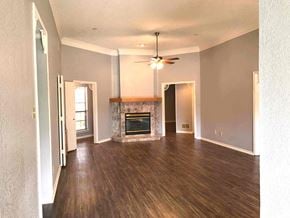 Garland house for rent - an empty living room with a fireplace and a ceiling fan