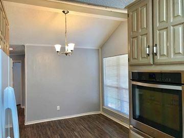 Garland house for rent - a kitchen with a stove and a microwave and a wall with white cabinets