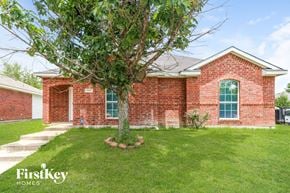 Dallas house for rent - A red brick house with a tree in front and a white garage door.