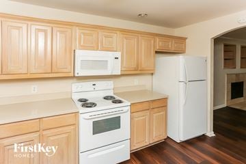Dallas house for rent - A kitchen with wooden cabinets and white appliances.