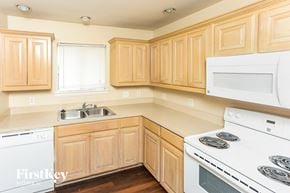 Dallas house for rent - A kitchen with wooden cabinets and white appliances.