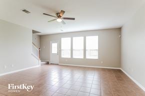 Baytown house for rent - an empty living room with a ceiling fan and large windows