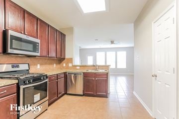 Baytown house for rent - a kitchen with wooden cabinets and a stove and a microwave
