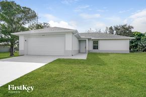 Lehigh Acres house for rent - a white house with a lawn and a garage door