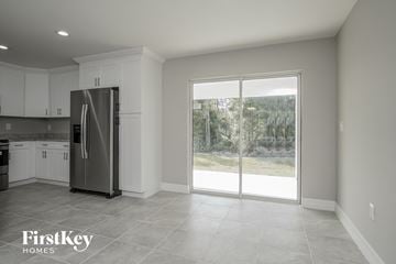 Lehigh Acres house for rent - a kitchen with a stainless steel refrigerator and white cabinets