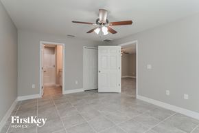Lehigh Acres house for rent - a living room with a ceiling fan and a door to a bathroom