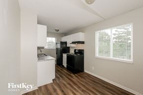 Indianapolis house for rent - A kitchen with white cabinets and a black fridge.