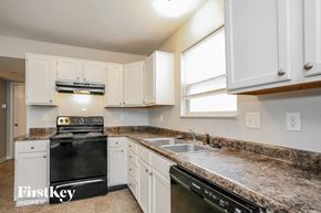 Indianapolis house for rent - a kitchen with white cabinets and granite counter tops and black appliances