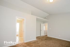 Indianapolis house for rent - a master bedroom with a carpeted floor and a door to a bathroom