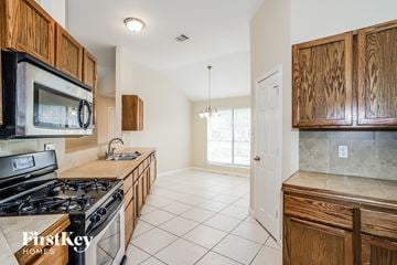 Houston house for rent - A kitchen with wooden cabinets and a stove top oven.