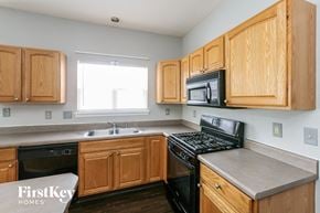 Indianapolis house for rent - a kitchen with wooden cabinets and black appliances and a window