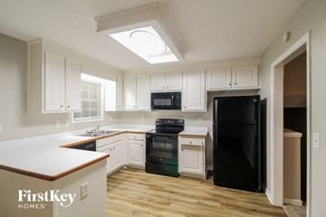 Lula house for rent - A kitchen with a black fridge and white cabinets.