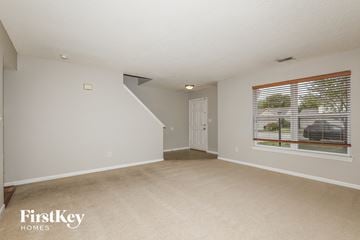 Indianapolis house for rent - a spacious living room with a large window and beige carpet