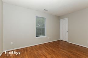 Indianapolis house for rent - a bedroom with wood flooring and a window and a white door