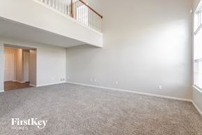Indianapolis house for rent - A spacious empty room with a carpeted floor and a staircase with a railing.