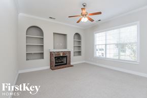 Trussville house for rent - a living room with a fireplace and a ceiling fan