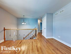 Matteson house for rent - the upstairs landing of a house with a staircase and blue walls and wood floors