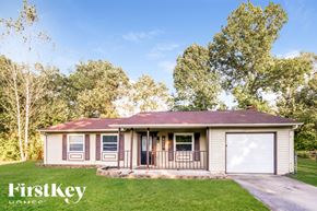 Indianapolis house for rent - A house with a brown roof and a garage door is surrounded by trees.