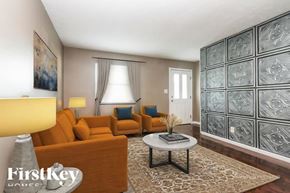 Indianapolis house for rent - A living room with a brown sofa, a grey coffee table, and a glass block wall.