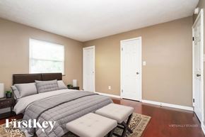 Indianapolis house for rent - A bedroom with a bed, two windows, and a rug.