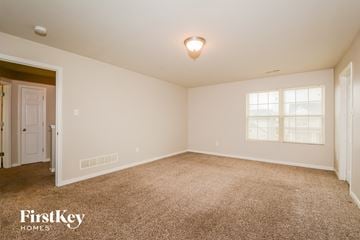 Florissant house for rent - a spacious living room with carpet and a door to a bedroom