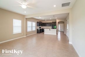 Jacksonville house for rent - A spacious living room with a kitchen in the background and a ceiling fan above.