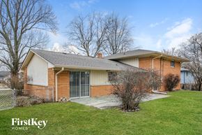 Indianapolis house for rent - A house with a brown brick exterior and a white garage door is for sale.