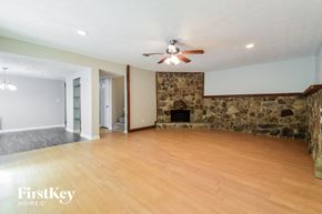 Lilburn house for rent - a living room with a stone fireplace and a ceiling fan