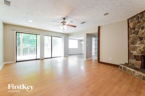 Lilburn house for rent - an empty living room with a stone fireplace and a ceiling fan