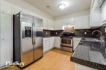 Lilburn house for rent - a kitchen with stainless steel appliances and white cabinets