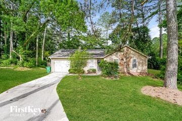 Lithonia house for rent - a small brick house with a driveway and a lawn and trees