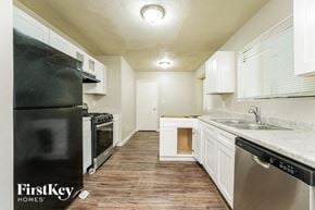 Lithonia house for rent - a kitchen with white cabinets and stainless steel appliances and a black refrigerator