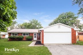 Indianapolis house for rent - A house with a red brick exterior and a white garage door is for sale.