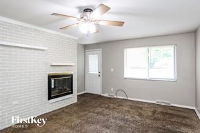 Indianapolis house for rent - A room with a fireplace and a ceiling fan.