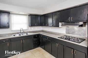 Indianapolis house for rent - A kitchen with black cabinets and a stove top oven.