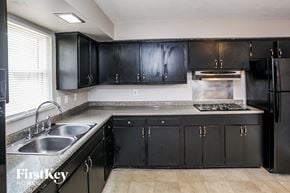 Indianapolis house for rent - A kitchen with black cabinets and a stainless steel sink.