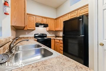 Memphis house for rent - A kitchen with a black refrigerator, sink, and stove top oven.