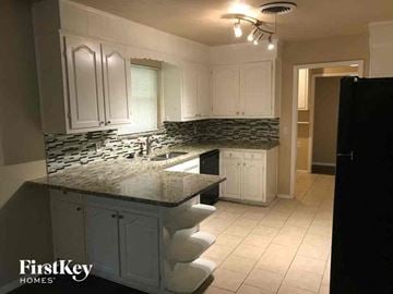 Fort Worth house for rent - a kitchen with white cabinets and a counter top