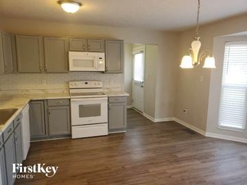 Maineville house for rent - A kitchen with wooden floors and a white stove top oven.
