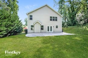 Charlotte house for rent - a white house with a concrete driveway and a lawn and trees