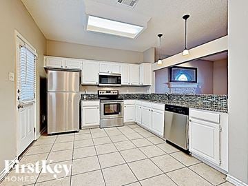 Arlington house for rent - a large kitchen with white cabinets and stainless steel appliances