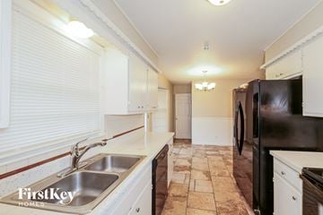 Kansas City house for rent - A kitchen with a black refrigerator and white cabinets.