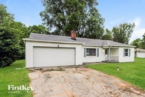 Indianapolis house for rent - A white house with a garage is surrounded by greenery.