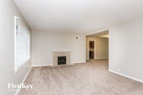 Indianapolis house for rent - A spacious, empty room with a fireplace and a carpeted floor.